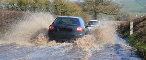 Car driving through a flooded road in East Devon